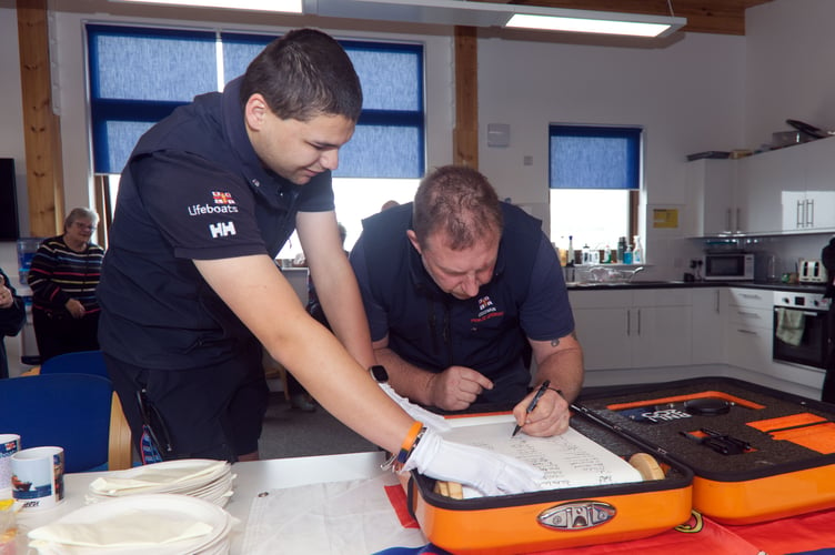 RNLI Coxswain Patch Harvey signing the scroll