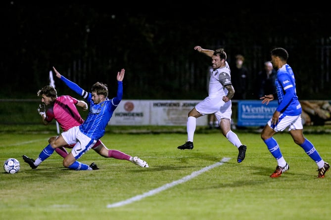 St Austell striker Liam Eddy wheels away in celebration as Buckland Athletic goalkeeper Adam Seedhouse-Evans and a defender look to clear his shot. Picture: Paul Williams