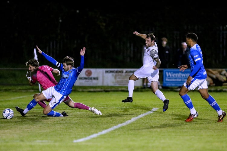 St Austell striker Liam Eddy wheels away in celebration as Buckland Athletic goalkeeper Adam Seedhouse-Evans and a defender look to clear his shot. Picture: Paul Williams