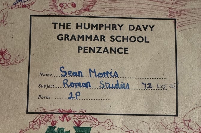 A schoolbook dated from 1975 found at Humphry Davy School, Penzance, Cornwall, has been reunited with itÕs original owner after nearly five decades. Release date November 25 2024. A former pupil has reunited with an exercise book discovered in a school drawer - after nearly five decades. The exercise book with work dated in 1975 was recently found at Humphry Davy School, Penzance, Cornwall, tucked in the back of a drawer in Room 31.  The book - filled with neat handwriting and labelled sketches - belonged to then student Sean Morris. Sean was then invited back to his former school where he was reunited with the book. The book was found by the school's current history teacher, Mr Morgan, who was organising his classroom over half term. Among faded paper and outdated textbooks, he found the exercise book - its beige cover worn but still intact, with "Sean Morris, Roman Studies, 2P" written on the front in blue ink.  