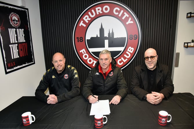 Truro City manager John Askey (centre) signs his new contract watched by Alex Black (football consultant) and Eric Perez (executive chairman)