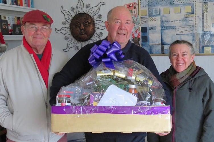 Lion Geoff Kaye presents a prize hamper to winners Frank and Sue Found from Veryan