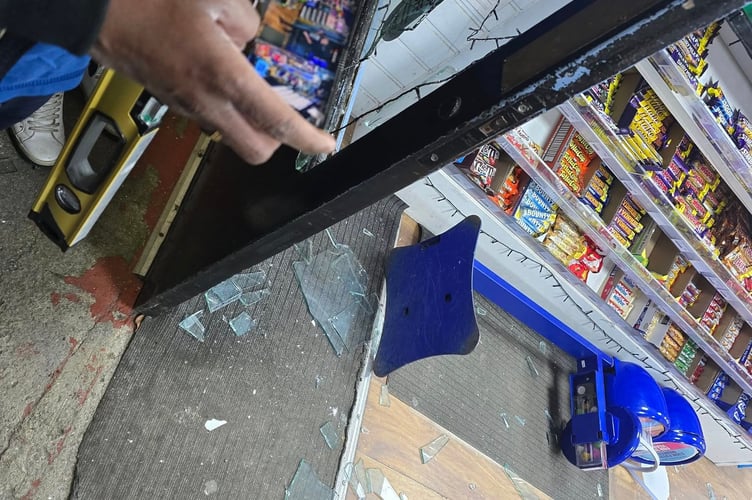 The broken shop window at Muthu's Mini Market in Saltash